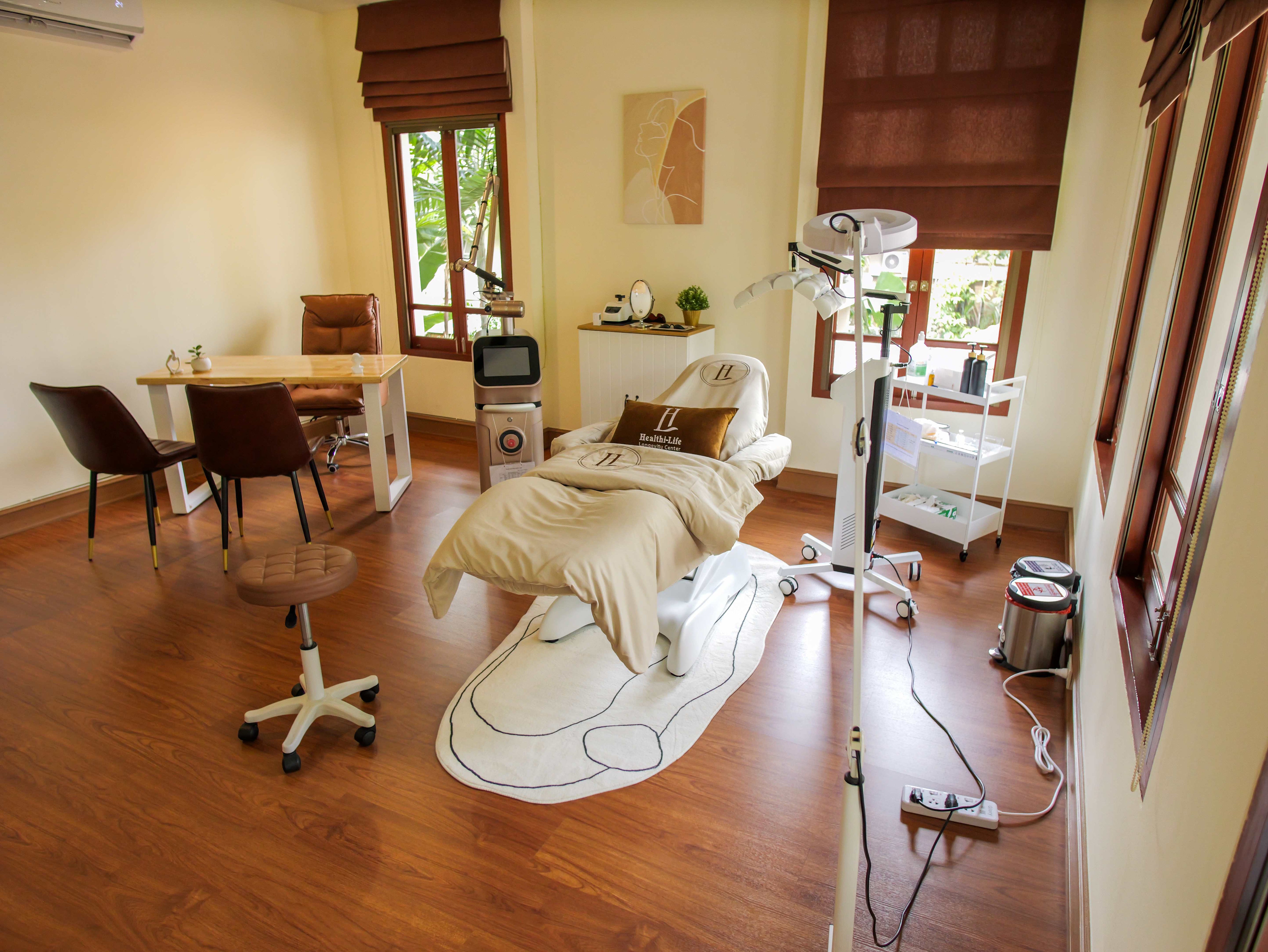 Private aesthetic treatment room at Healthi-Life Bangkok with natural light, luxury reclining bed, and premium skincare equipment for facial and regenerative therapies.