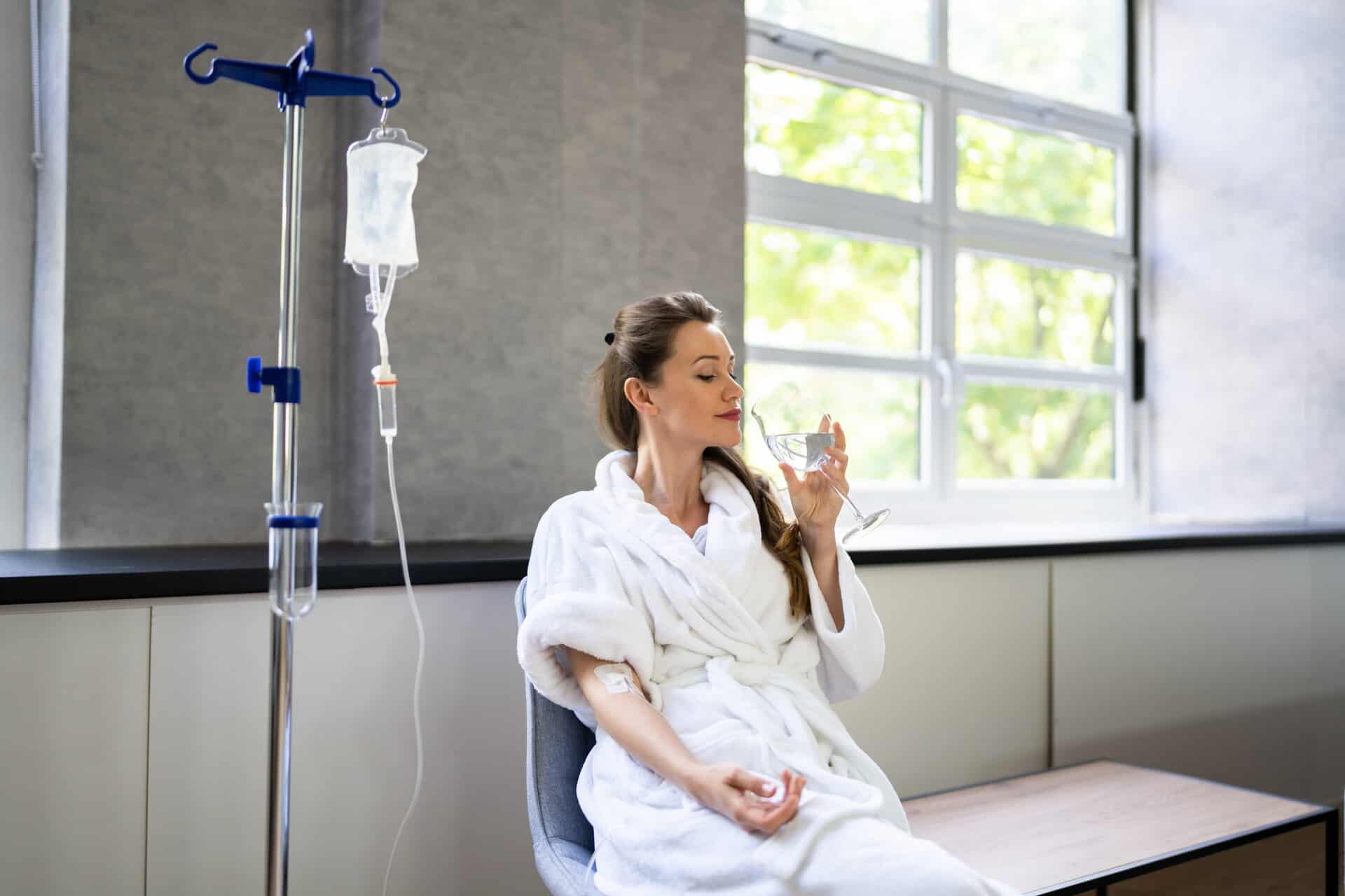 Woman in a robe gets IV therapy while enjoying a refreshment
